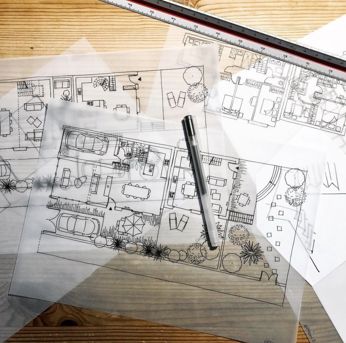 Calques et plans dessinés à la main posés sur la table de travail, stylo et réglet.